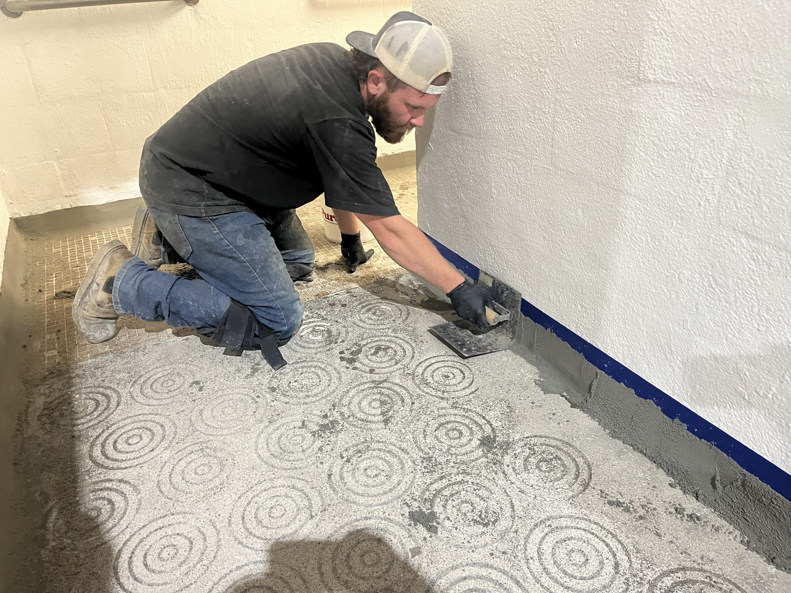 Installer completing detailed floor preparation along a wall